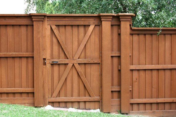 medium brown stained wood fence and gate with an x pattern at the front of the gate.